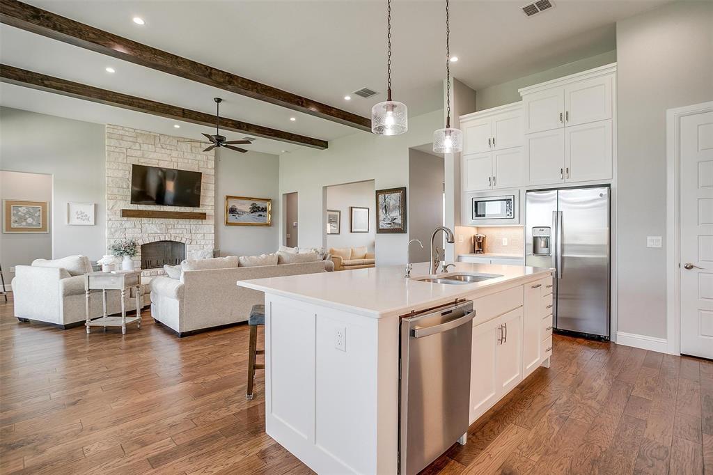7730 Barber Rnch Road Fort Worth, TX 76126 - Photo 13 of 19 Kitchen island with white cabinetry, stainless steel sink, and pendant lighting