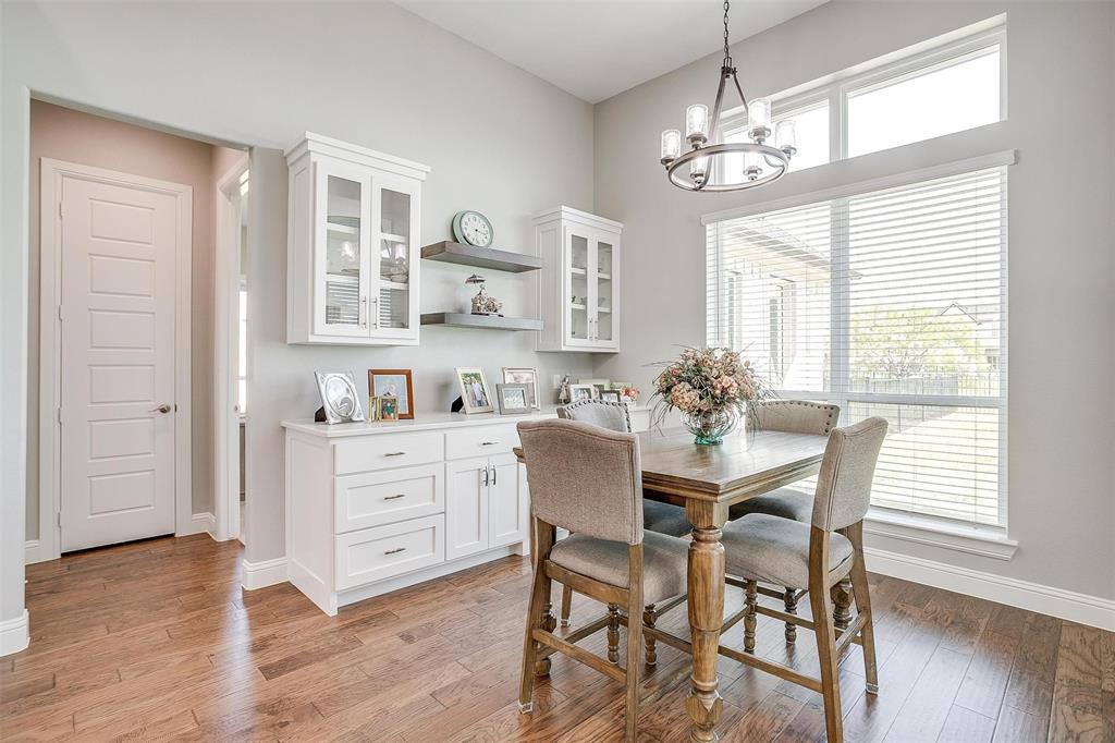 7730 Barber Rnch Road Fort Worth, TX 76126 - Photo 15 of 19 Dining area featuring wood-finish flooring, white built-in cabinetry, and a tiered chandelier