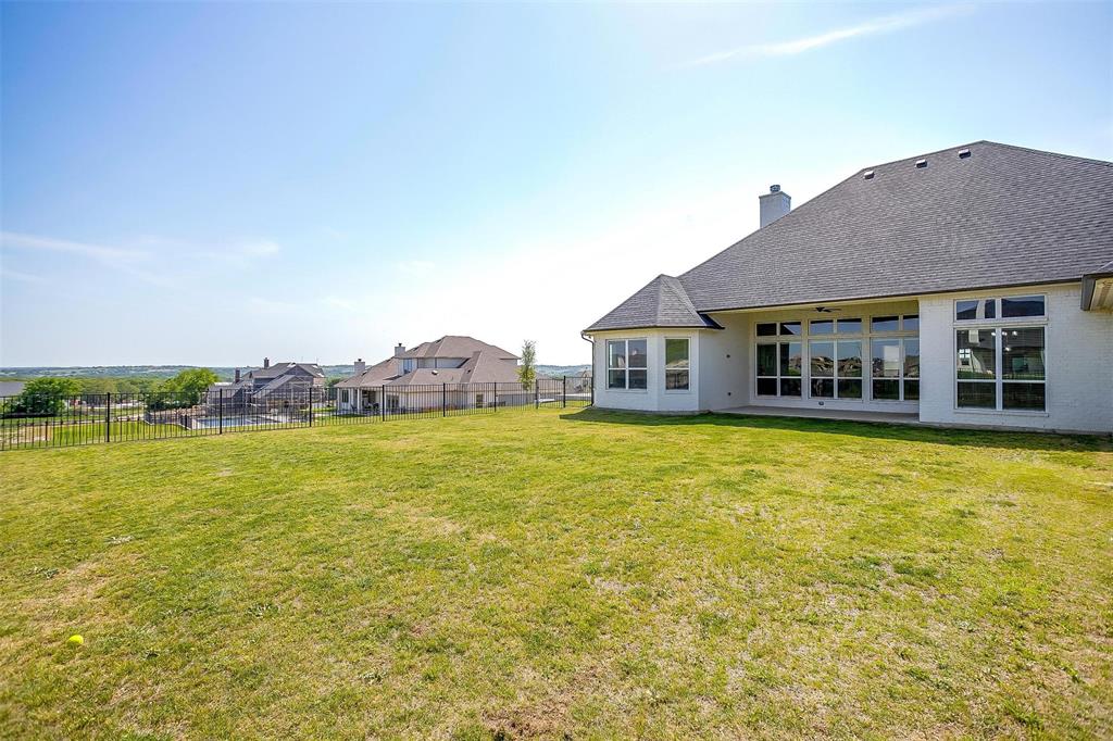 7730 Barber Rnch Road Fort Worth, TX 76126 - Photo 19 of 19 Expansive rear lawn featuring a white stucco exterior, multiple large windows, a covered patio area, and a privacy fence