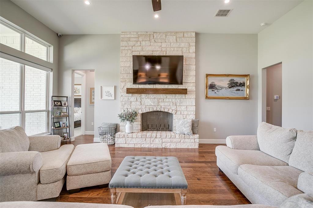 7730 Barber Rnch Road Fort Worth, TX 76126 - Photo 6 of 19 Spacious living area featuring a stone-clad fireplace with a wood mantel, high ceilings, wood-finish flooring, and large windows with transom panels