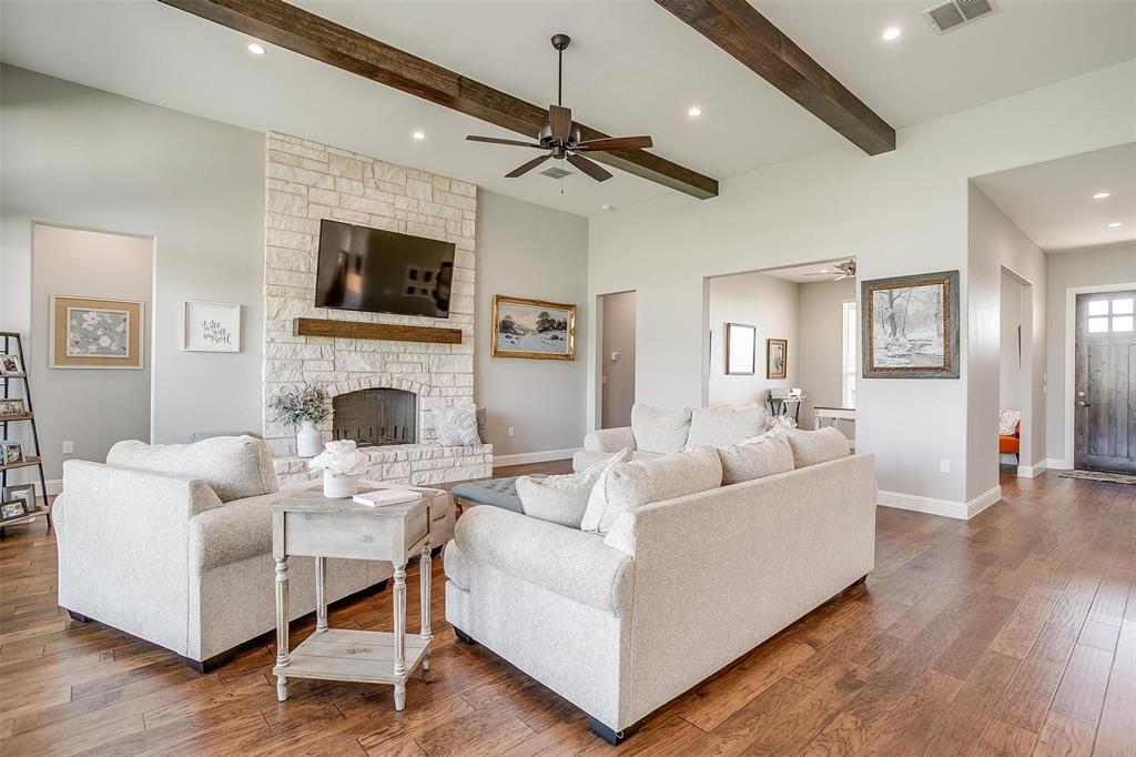 7730 Barber Rnch Road Fort Worth, TX 76126 - Photo 7 of 19 Spacious living area featuring a stone fireplace, wood-finish flooring, exposed ceiling beams, recessed lighting, and a prominent dark wood entry door