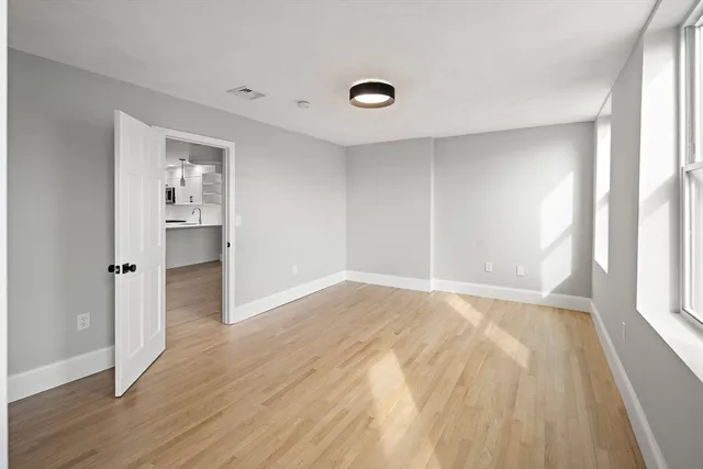 a view of an empty room with wooden floor and a window