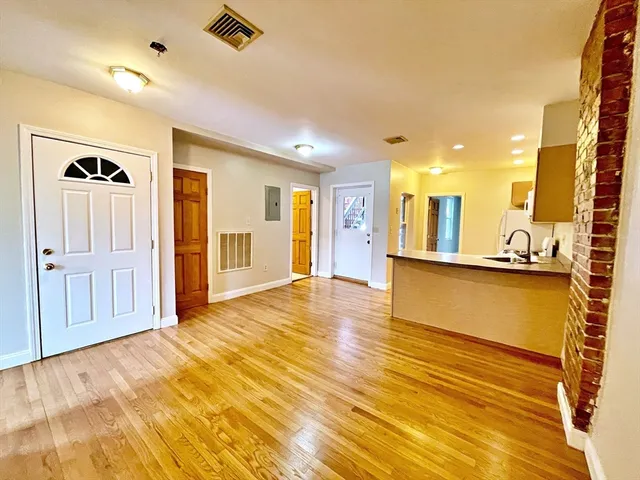 a view of a livingroom with kitchen space and wooden floor