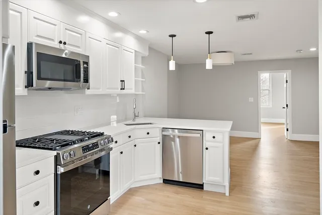 a kitchen with granite countertop a sink a stove and wooden floor