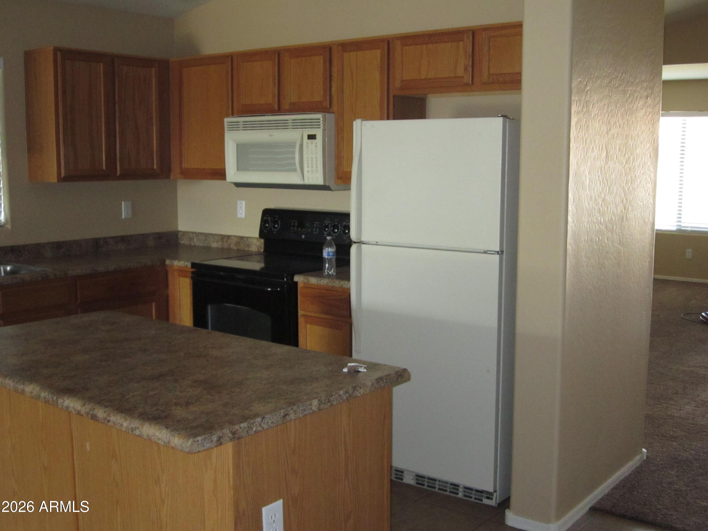 18671 North Madison Road Maricopa, AZ 85139 - Photo 2 of 27 a kitchen with a refrigerator and a stove top oven