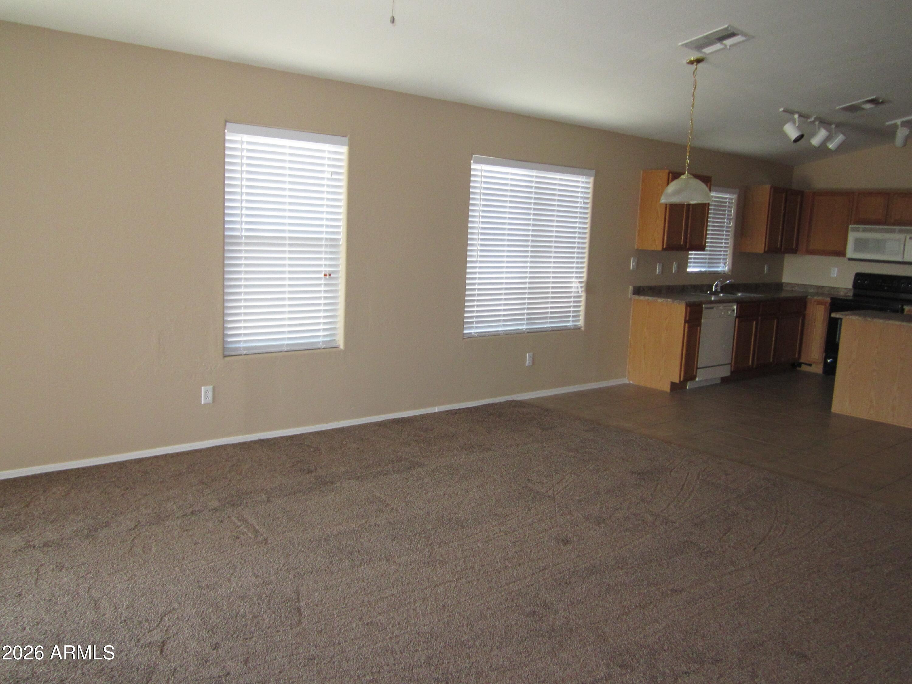 18671 North Madison Road Maricopa, AZ 85139 - Photo 4 of 27 a view of a kitchen with kitchen island granite countertop wooden cabinets a sink and a window