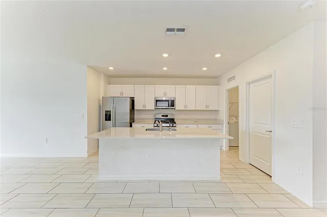 a view of kitchen with stainless steel appliances dining table and chair