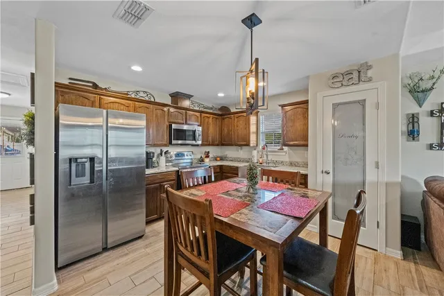 a kitchen with a dining table chairs stainless steel appliances and cabinets