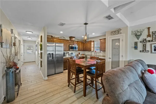 a kitchen with stainless steel appliances kitchen island granite countertop a refrigerator a stove a microwave oven a dining table and chairs with wooden floor