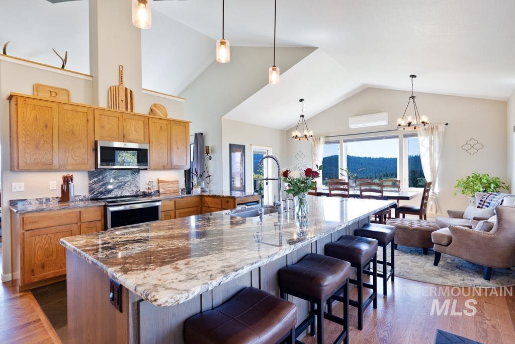 1049 Libey Road Viola, ID 83872 - Photo 11 of 43 Open-concept living space featuring a spacious kitchen island with seating, natural wood cabinetry, stainless steel appliances, and vaulted ceilings