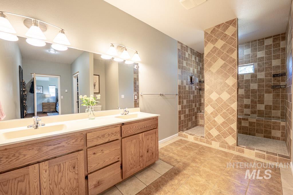 1049 Libey Road Viola, ID 83872 - Photo 16 of 43 Bathroom featuring a double vanity with wood cabinetry, a large mirror, and two tiled shower stalls