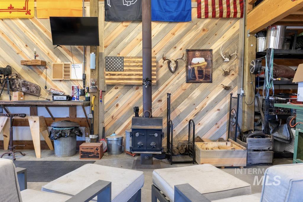 1049 Libey Road Viola, ID 83872 - Photo 31 of 43 Wood-finish diagonal accent wall featuring a wall-mounted television and a built-in wood-burning stove with a metal flue