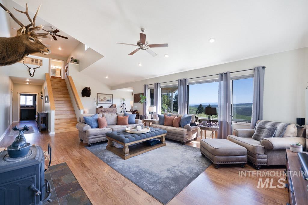 1049 Libey Road Viola, ID 83872 - Photo 10 of 43 Spacious living area featuring wood-finish flooring, a vaulted ceiling with recessed lighting and ceiling fans, and a built-in wood-burning stove on a slate tile hearth