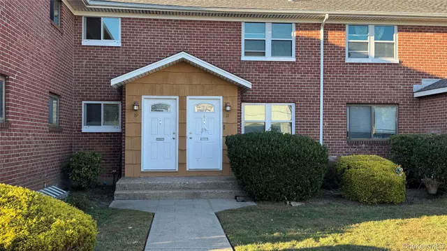 a view of a brick house many windows and yard in front of it