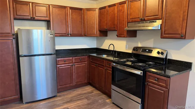 a kitchen with granite countertop wooden cabinets and stainless steel appliances