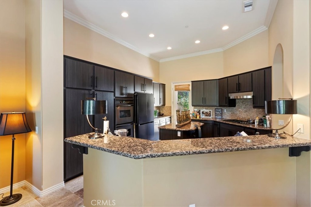 5614 Queen Palms Drive Riverside, CA 92506 - Photo 27 of 50 a kitchen with kitchen island granite countertop a sink and a refrigerator