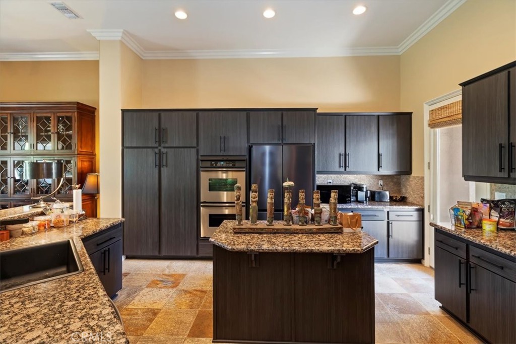 5614 Queen Palms Drive Riverside, CA 92506 - Photo 29 of 50 a kitchen with kitchen island granite countertop a stove refrigerator and cabinets