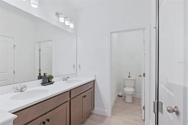 a bathroom with a double vanity sink toilet and a mirror