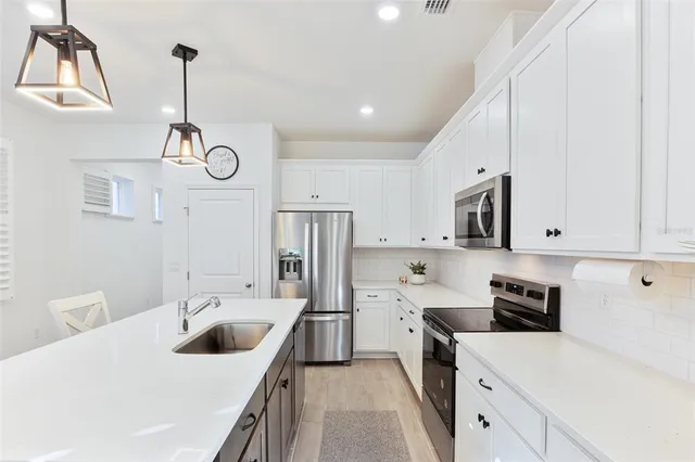 a kitchen with stainless steel appliances granite countertop a sink a stove and white cabinets with wooden floor