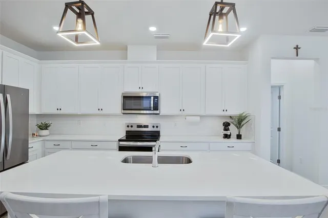 a white kitchen with a sink a stove a refrigerator and cabinets