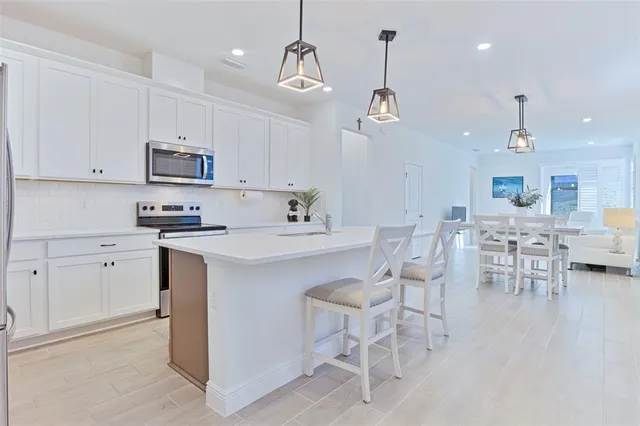 a kitchen with white cabinets and chairs