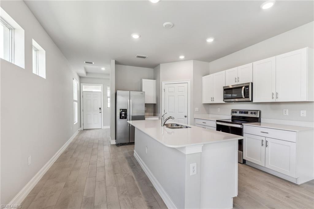 826 Friendship Circle LaBelle, FL 33935 - Photo 17 of 19 a large white kitchen with a refrigerator a stove top oven a sink dishwasher and white cabinets with wooden floor