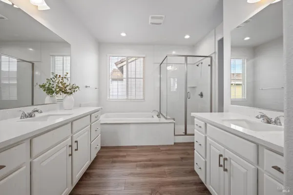 a spacious bathroom with double vanity a mirror a bathtub and a shower