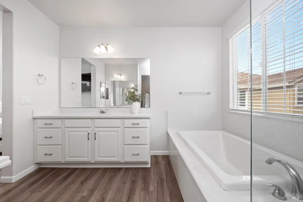 a bathroom with a bathtub a double vanity sink and a window