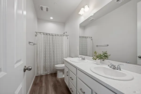 a bathroom with a double vanity sink toilet and a mirror