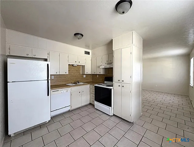 a kitchen with a refrigerator a stove top oven and cabinets