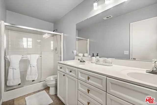 a bathroom with a double vanity sink toilet mirror and shower