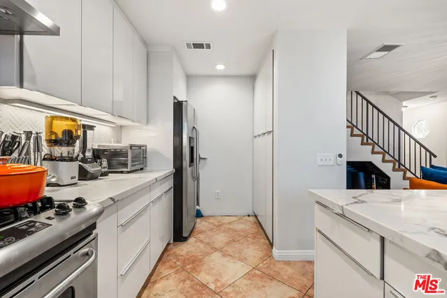 a kitchen with stainless steel appliances kitchen island granite countertop a sink a stove and a refrigerator