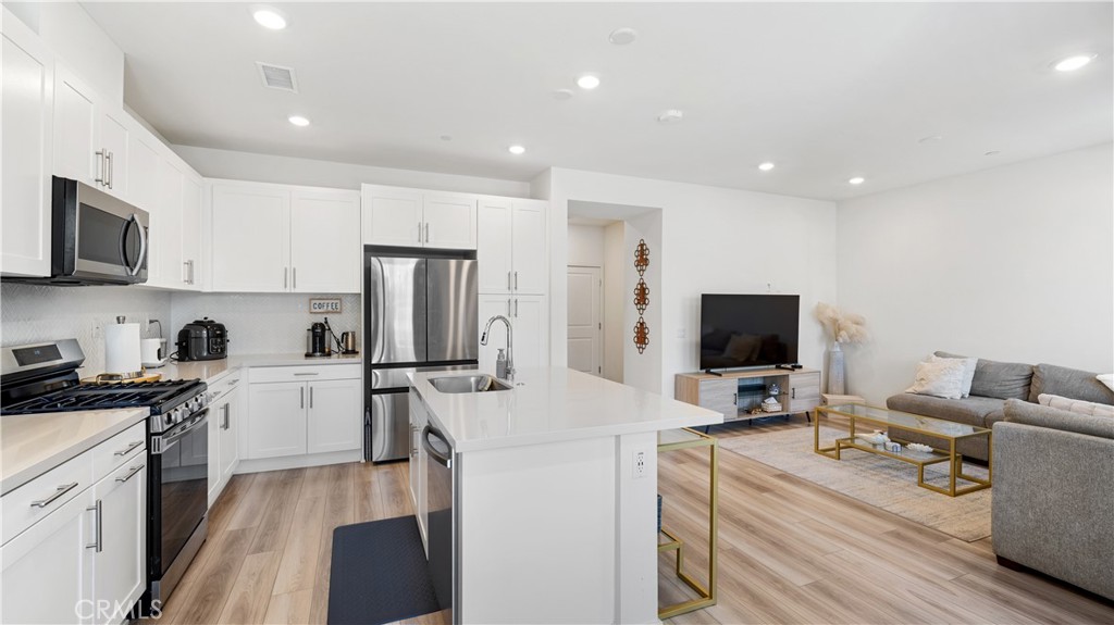 3610 East Pollock Street, Unit 4 Ontario, CA 91761 - Photo 12 of 47 a kitchen with a refrigerator a stove top oven a sink dishwasher and white cabinets with wooden floor