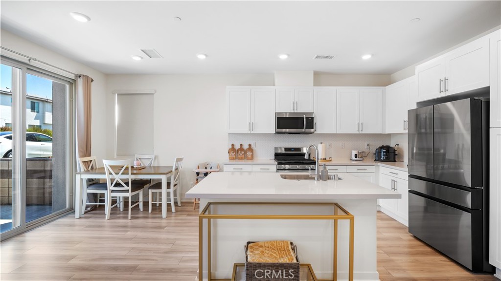 3610 East Pollock Street, Unit 4 Ontario, CA 91761 - Photo 13 of 47 a kitchen with stainless steel appliances a microwave a stove a refrigerator a stove top oven and a dining table with wooden floor
