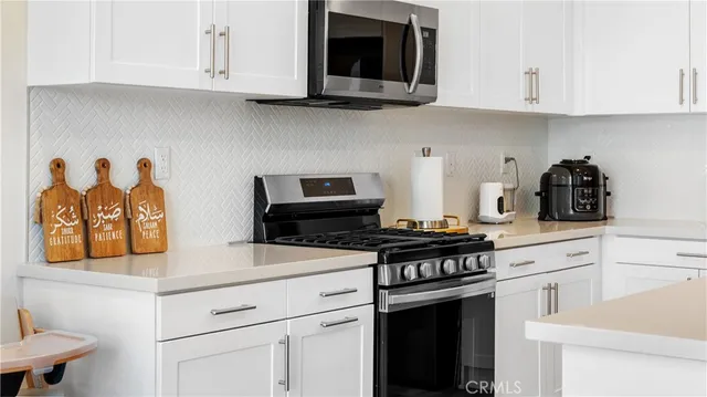 a kitchen with stainless steel appliances granite countertop white cabinets and a stove