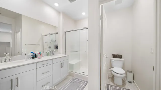 a bathroom with a double vanity sink toilet mirror and shower