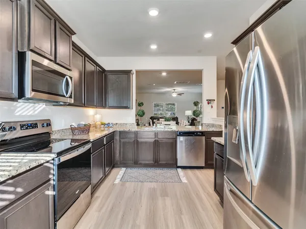 a kitchen with stainless steel appliances granite countertop a refrigerator a stove top oven a sink and dishwasher