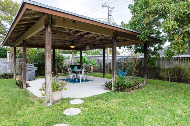 a view of a backyard with table and chairs under an umbrella with a small yard
