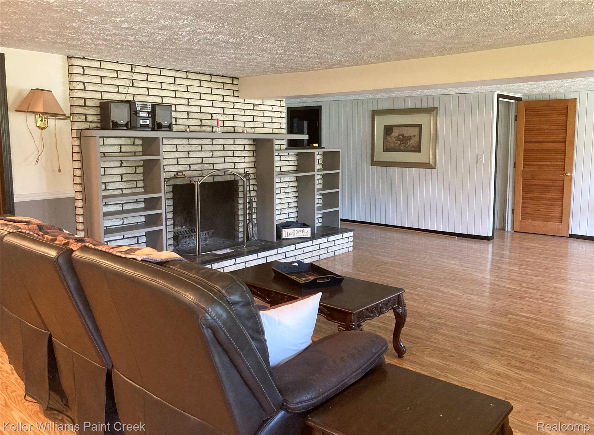 42891 Bemis Road Belleville, MI 48111 - Photo 16 of 51 Living area featuring wood finished floors, a fireplace, and a textured ceiling