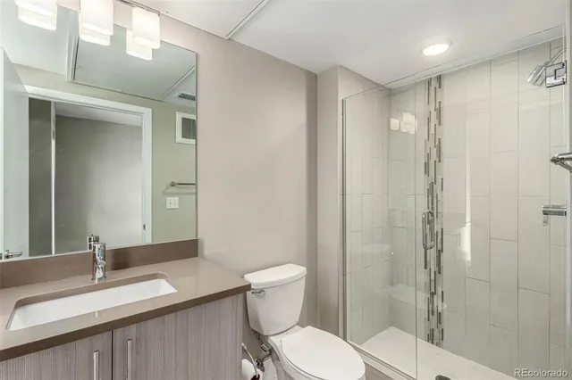 a bathroom with a granite countertop sink toilet a mirror a vanity and shower