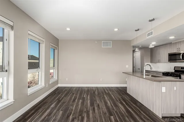 a kitchen with granite countertop a stove top oven a sink with wooden floors and cabinets