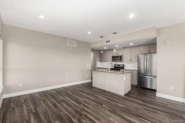 a kitchen with stainless steel appliances kitchen island granite countertop a refrigerator and a stove top oven