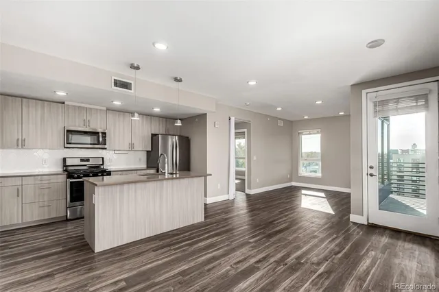 a kitchen with stainless steel appliances a stove top oven a refrigerator a sink dishwasher with wooden floor and cabinets