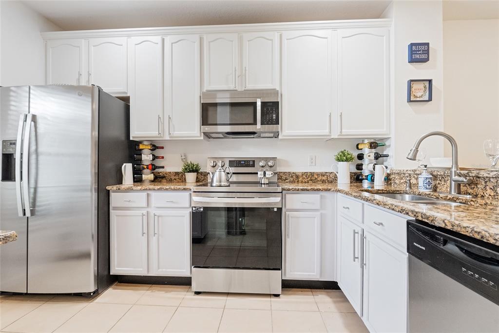 10475 Manderley Way Orlando, FL 32829 - Photo 10 of 31 a kitchen with stainless steel appliances granite countertop a refrigerator sink and white cabinets