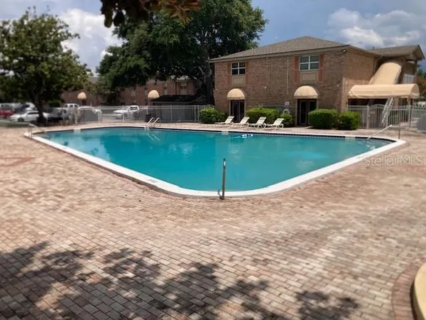 a view of a swimming pool and a chairs in front of house