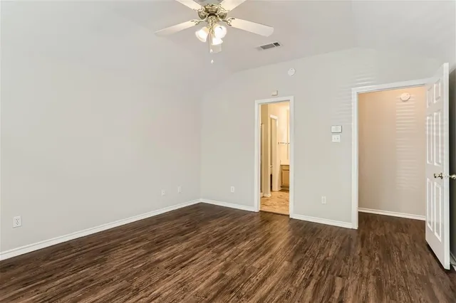 an empty room with wooden floor fan and windows