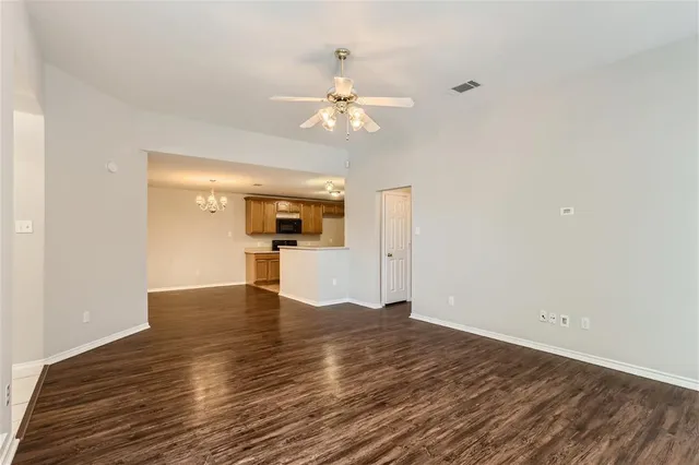 a view of empty room with wooden floor and ceiling fan