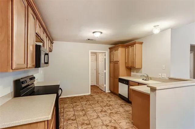 a kitchen that has a sink a stove and chairs