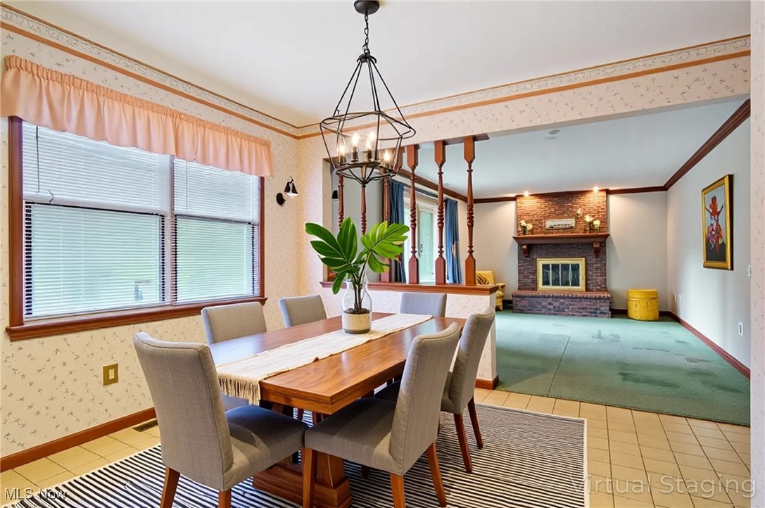 7300 Morley Road Painesville, OH 44077 - Photo 19 of 50 Dining room with wallpapered walls, light tile patterned flooring, a brick fireplace, ornamental molding, and a chandelier