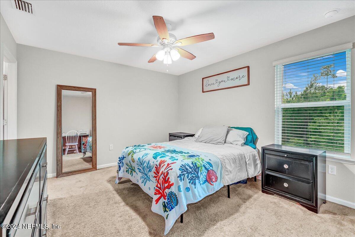 183 Silver Fern Drive St. Augustine, FL 32086 - Photo 18 of 29 a bedroom with a bed and a chandelier